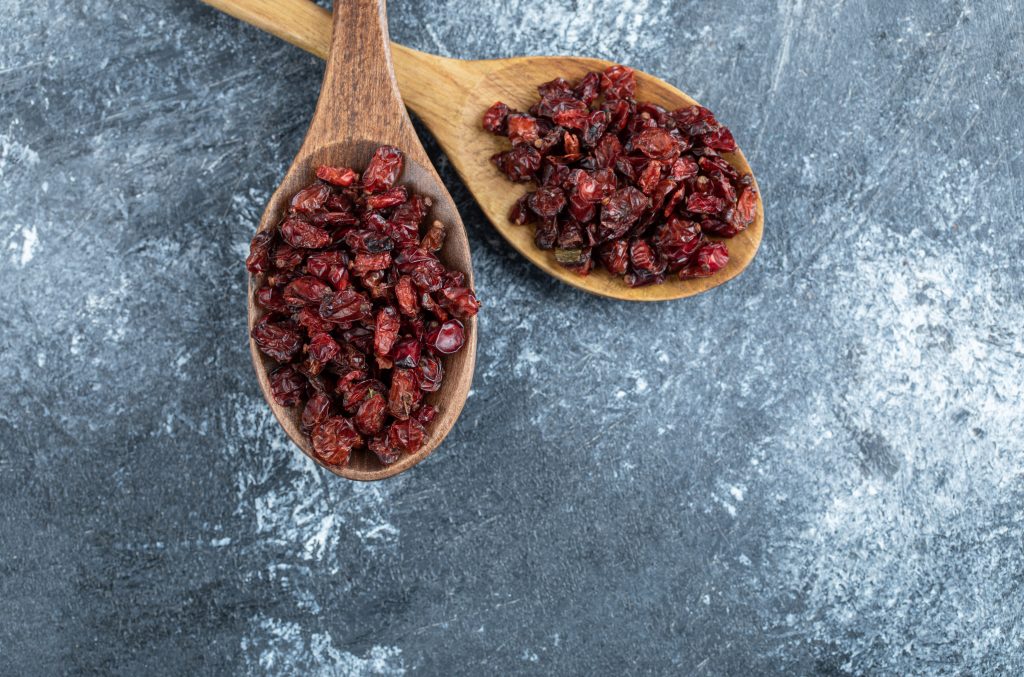 Two wooden spoons full of dried cranberries

